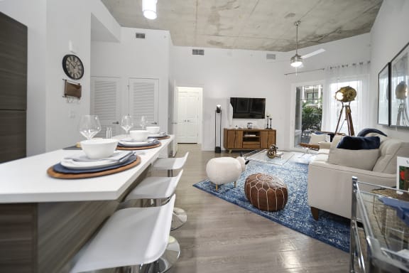 a living room and dining room with a white table and white chairs and a blue rug at Altis Grand Central, Tampa, FL