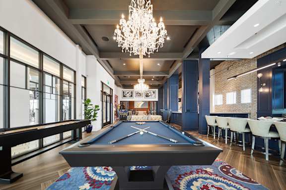 A pool table is in the middle of a room with a chandelier hanging from the ceiling.