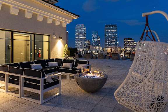 A white outdoor patio with a black couch and a fire pit.