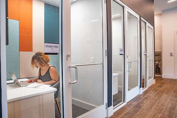A woman is working on her laptop in a study pod.