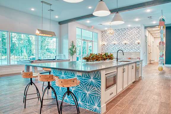 A kitchen with a blue and white patterned island and wooden bar stools.
