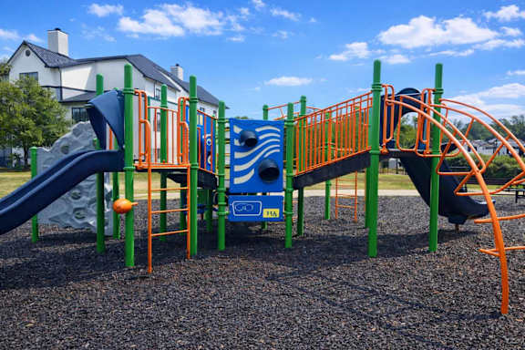 A playground with a blue slide and orange railings.