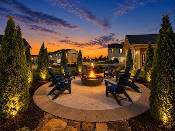 A backyard with a fire pit and chairs.