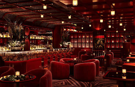 A dimly lit room with red chairs and tables.