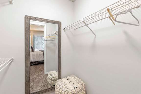 A white closet with a mirror and a shelf.