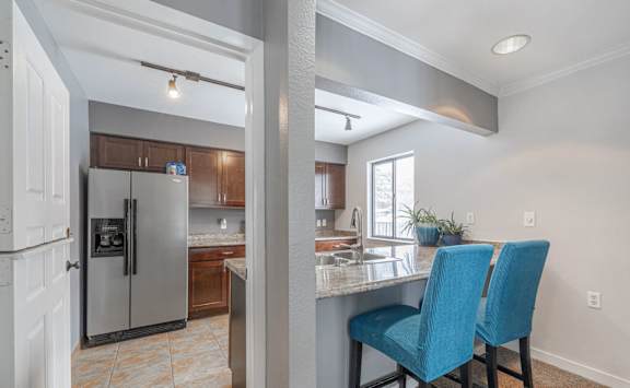A kitchen with a refrigerator, sink, and blue chairs at Winchell Way Apartment , Kalamazoo, Michigan