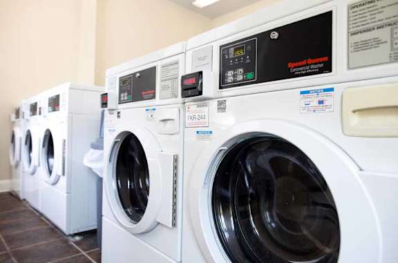 A row of white front load washing machines in a laundromat.