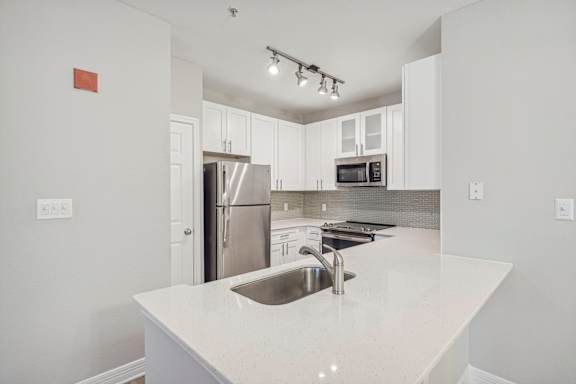 A kitchen with a white counter top and stainless steel appliances.
