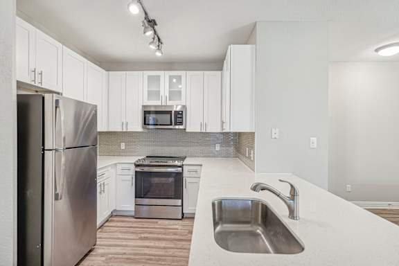 A modern kitchen with white cabinets and stainless steel appliances.