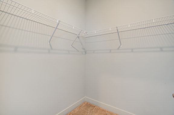 a walk in closet in a white room with shelves