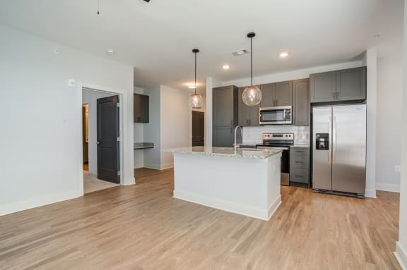 a kitchen with a large island and a stainless steel refrigerator