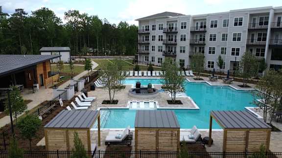 A large swimming pool surrounded by lounge chairs and trees.