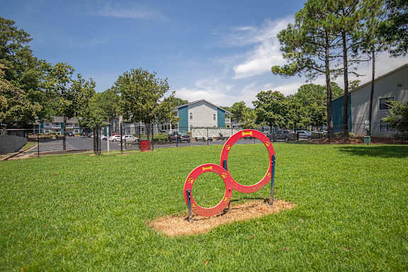 A red sculpture of three interlocking rings sits in a grassy field.