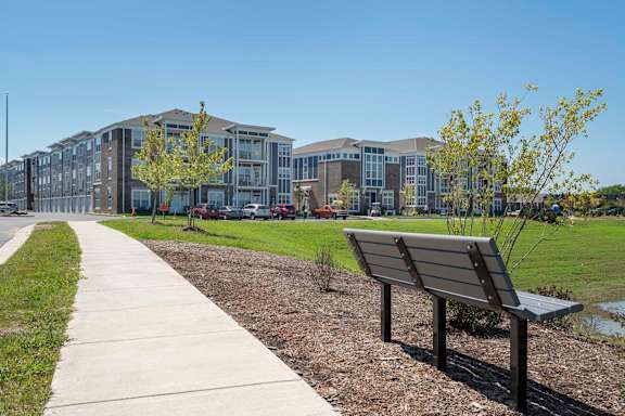 A bench is on the side of a concrete walkway.