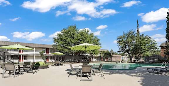 A pool area with sun loungers and umbrellas.
