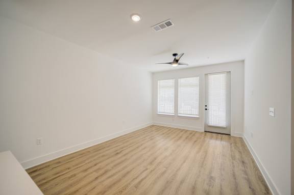 A room with a ceiling fan and a door with a window.