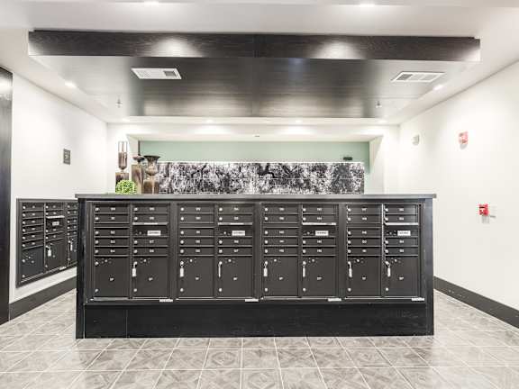 A black mailbox with a green wall in the background.