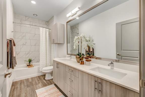 A bathroom with a white sink, a white toilet, a white bathtub, and a white shower curtain.
