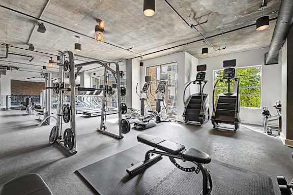 A gym with a variety of equipment including weights and cardio machines.