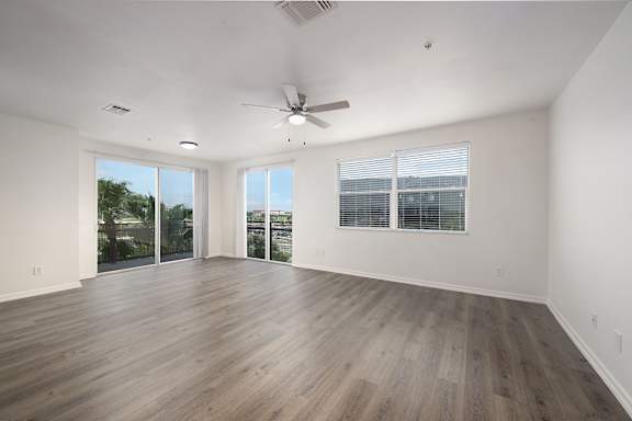 A spacious room with wooden flooring and a ceiling fan.