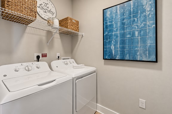 A laundry room with a washer and dryer and a painting on the wall.