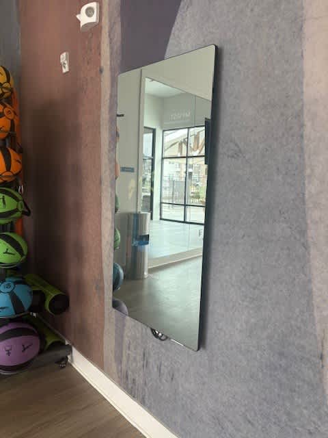 A mirror reflects a room with a door and a window.