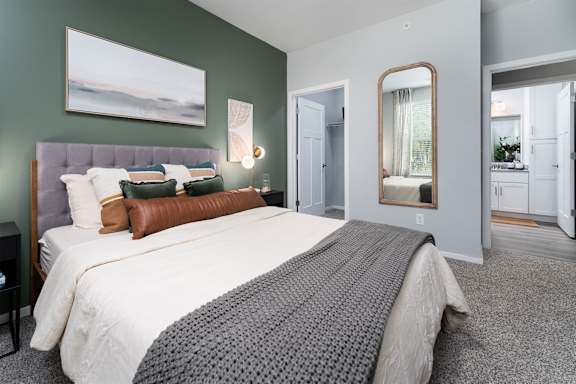 A bedroom with a large bed and a painting on the wall.