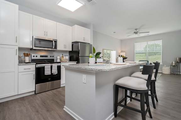 A kitchen with a white island and black bar stools.