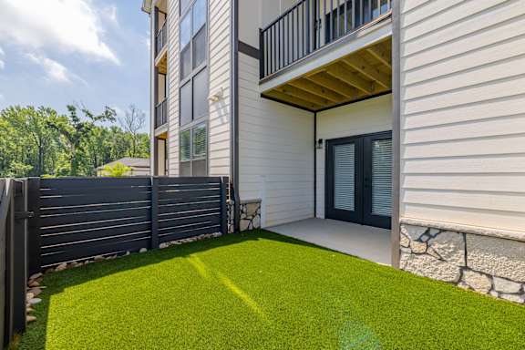 A small backyard with a wooden deck and a black fence.