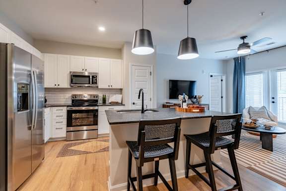 A modern kitchen with a refrigerator, microwave, oven, and sink.
