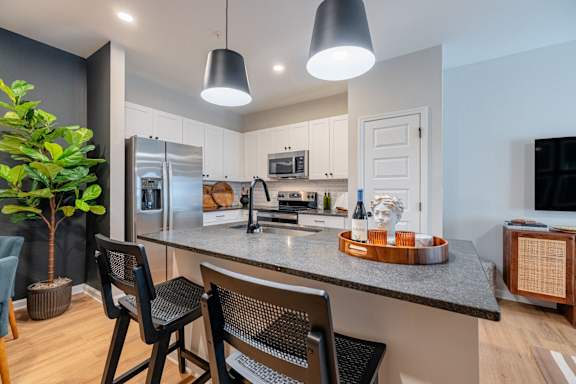 A modern kitchen with a dark wood floor and white walls.