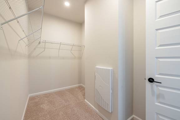 A white closet with a white door and a white radiator on the wall.