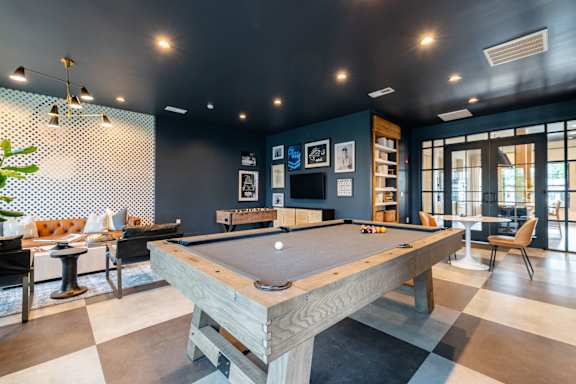 A pool table in a room with a dark wall and a light-colored floor.