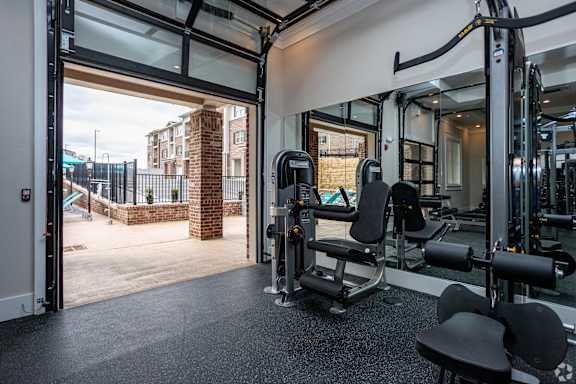 a gym with cardio machines and glass doors with a view of a building