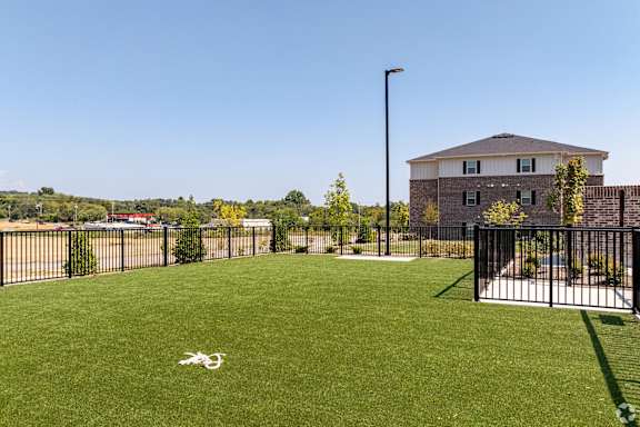 the yard is fenced in with a house in the background