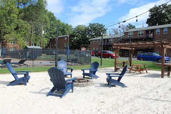 Beach chairs and picnic tables are arranged on a sandy beach.