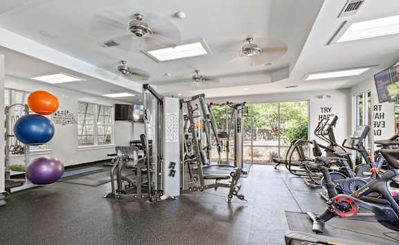 A gym with a variety of equipment including treadmills, weights, and exercise balls.