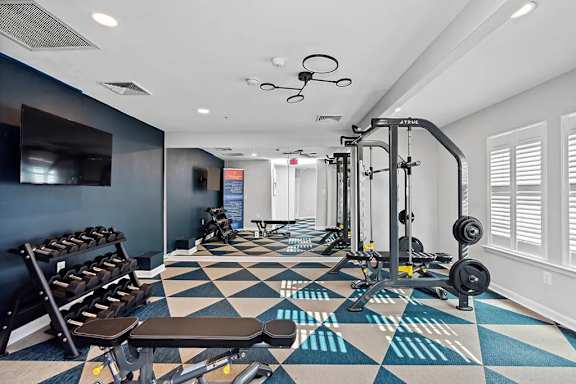 A gym with a variety of equipment including weights and benches.