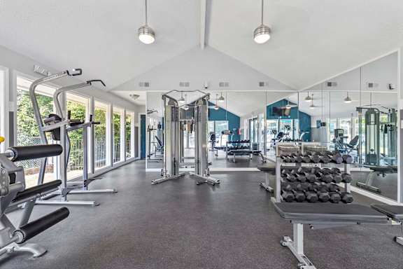 A spacious gym with a variety of equipment and a large mirror on the wall.