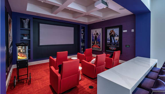a theater room with red chairs and a projector screen at Altis Grand Lake Willis, Orlando, FL 32821
