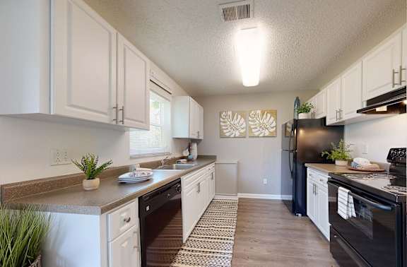 A kitchen with white cabinets and a black refrigerator