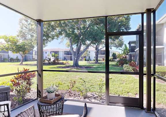 A patio with a table and chairs overlooks a green lawn