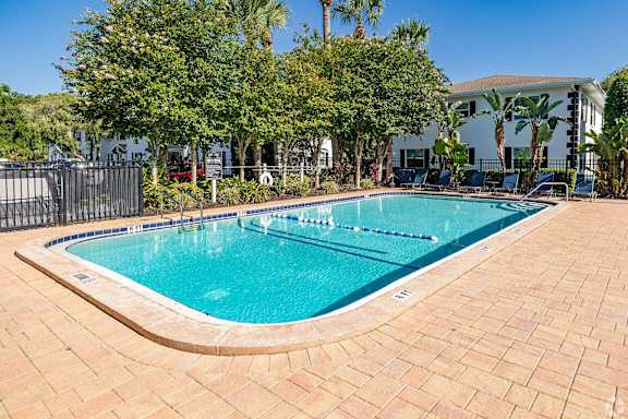 A small pool surrounded by a brick patio and trees