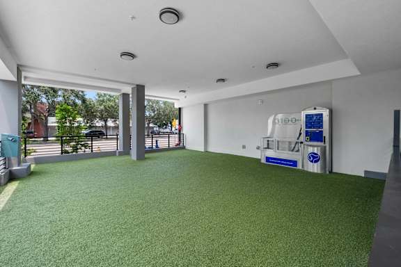 A large room with a green carpet and a white wall with a blue and white object on it.
