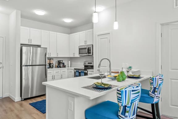 A kitchen with a white counter and blue chairs.