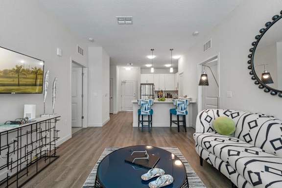 A living room with a black and white patterned couch and a coffee table with a pair of baby shoes on it.