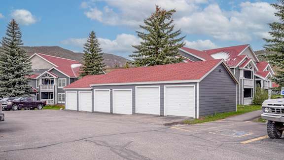A large grey building with a red roof is surrounded by a parking lot.