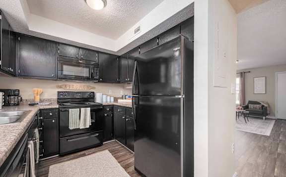 A black fridge in a kitchen with black cabinets.