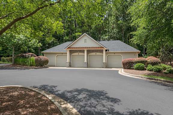 A house with a grey roof and a white garage door is surrounded by greenery.
