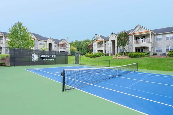 A tennis court is in front of a sign that says Greystone Properties.